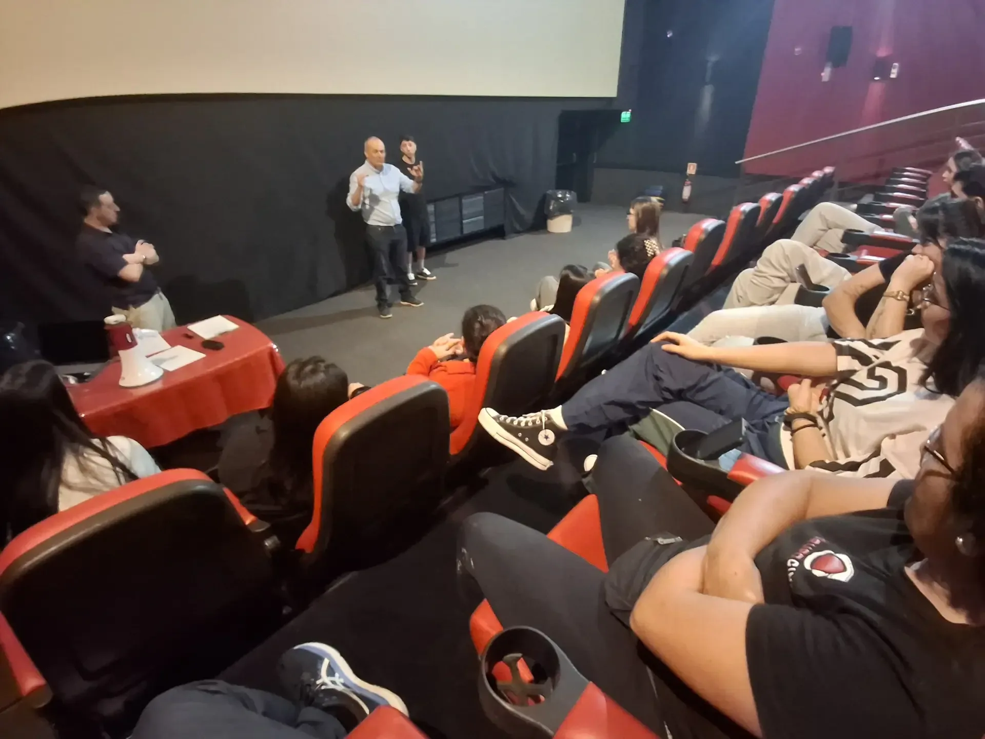 Instancia de explicación y coordinación en auditorio, con expositor, participantes y megáfono